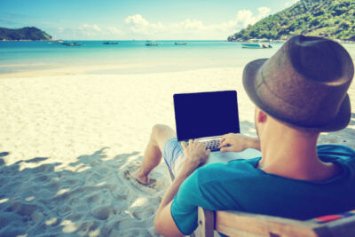 Attractive young man with laptop working on the beach. Freedom, remote work, freelancer, technology, internet, travel and vacation concepts © olezzo Adobe Stock