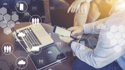 Close-up laptop and digital tablet on table, smartphone in men’s hands. Virtual icons with clouds, people, gadgets ©foxyburrow - stock.adobe.com